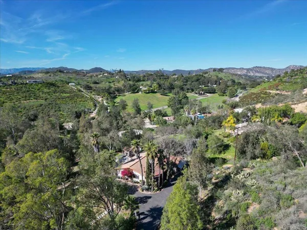 an aerial view of residential house with outdoor space and trees all around