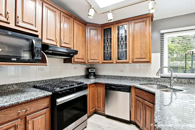 a kitchen with granite countertop cabinets stainless steel appliances a sink and a window