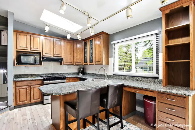 a kitchen with stainless steel appliances granite countertop wooden cabinets a stove a sink and a microwave
