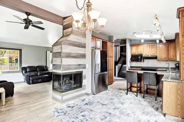 a living room with stainless steel appliances kitchen island granite countertop furniture and a fireplace