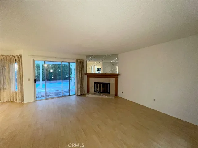 an empty room with floor to ceiling window and fireplace