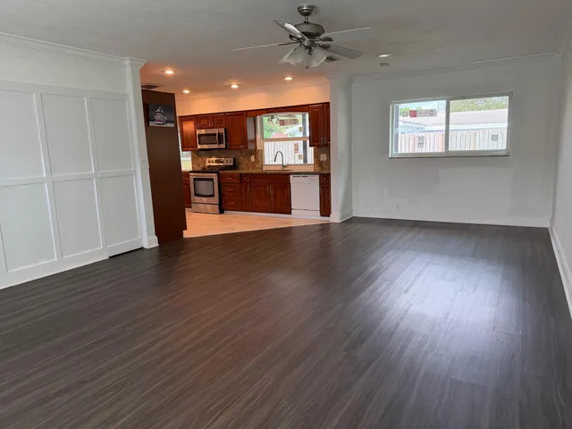 a view of an empty room with wooden floor and a window