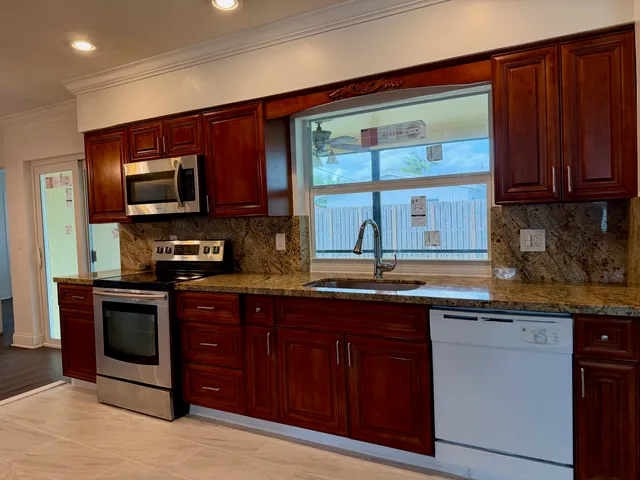 a kitchen with stainless steel appliances granite countertop a stove sink microwave and window