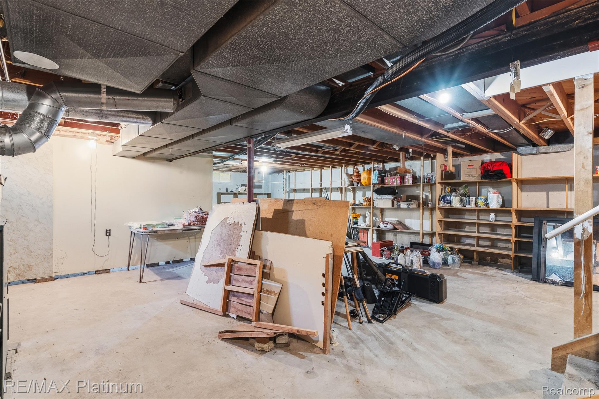 8370 West Rolston Road Linden, MI 48451 - Photo 28 of 36 Expansive unfinished basement featuring concrete flooring, exposed ceiling joists, exposed ductwork, perimeter shelving, and a wood staircase