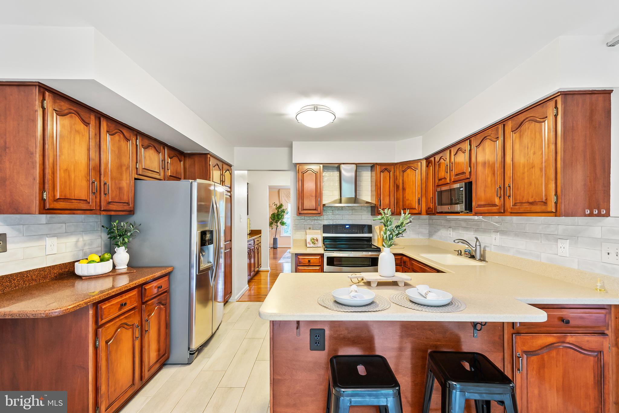 7443 Crestberry Lane Bethesda, MD 20817 - Photo 13 of 46 a kitchen with stainless steel appliances a stove top oven a refrigerator a sink and dishwasher with wooden floor
