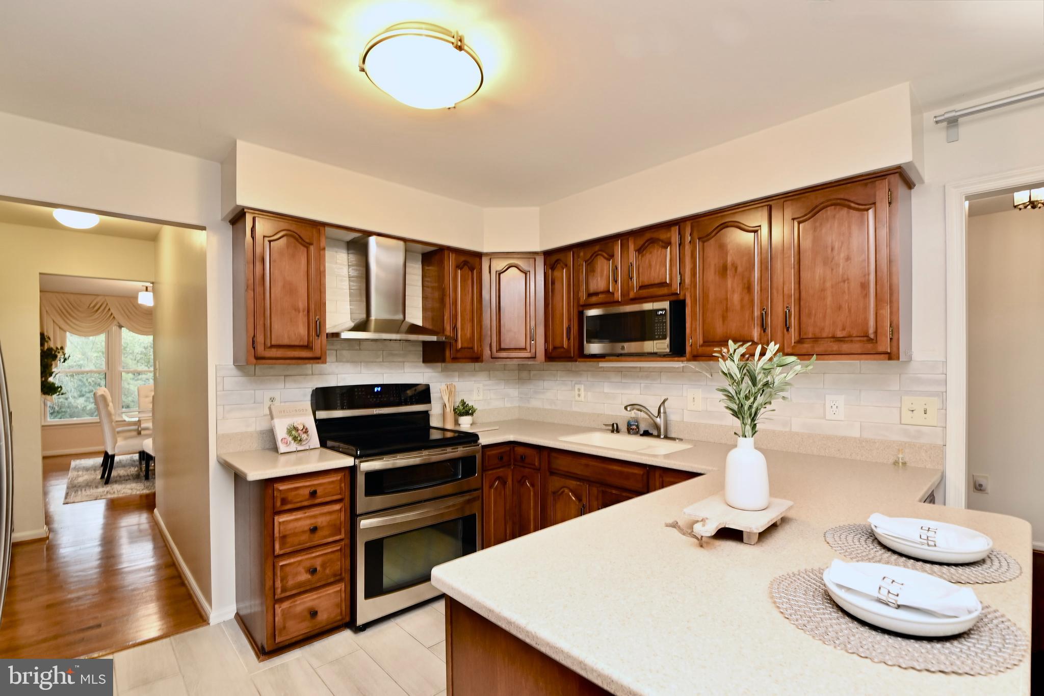 7443 Crestberry Lane Bethesda, MD 20817 - Photo 14 of 46 a kitchen with granite countertop a stove a sink dishwasher a dining table and chairs with wooden floor