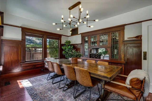 a dining room with wooden floor a chandelier a wooden table and chairs