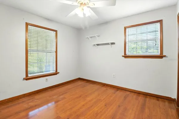a view of an empty room with a window and wooden floor