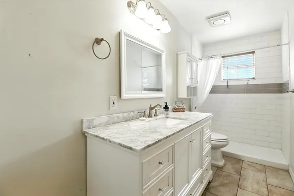 a bathroom with a granite countertop sink a toilet and a mirror