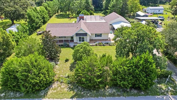 an aerial view of residential house with outdoor space and trees all around