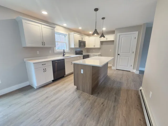 a large kitchen with wooden floors and white cabinets