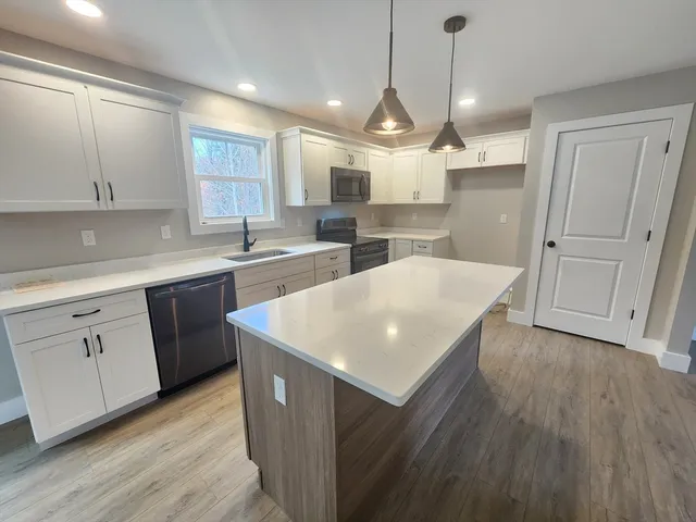 a kitchen with wooden floors and white cabinets