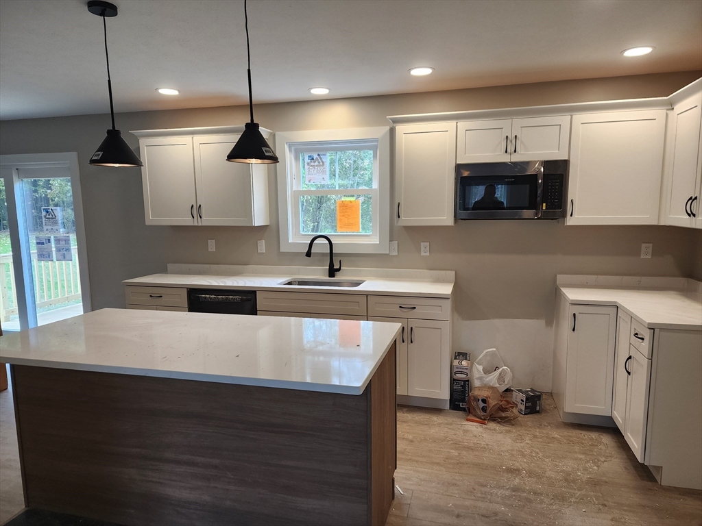 21 Cottage Street Winchendon, MA 01475 - Photo 4 of 12 a kitchen with kitchen island a counter space a sink and a stove top oven with wooden floor
