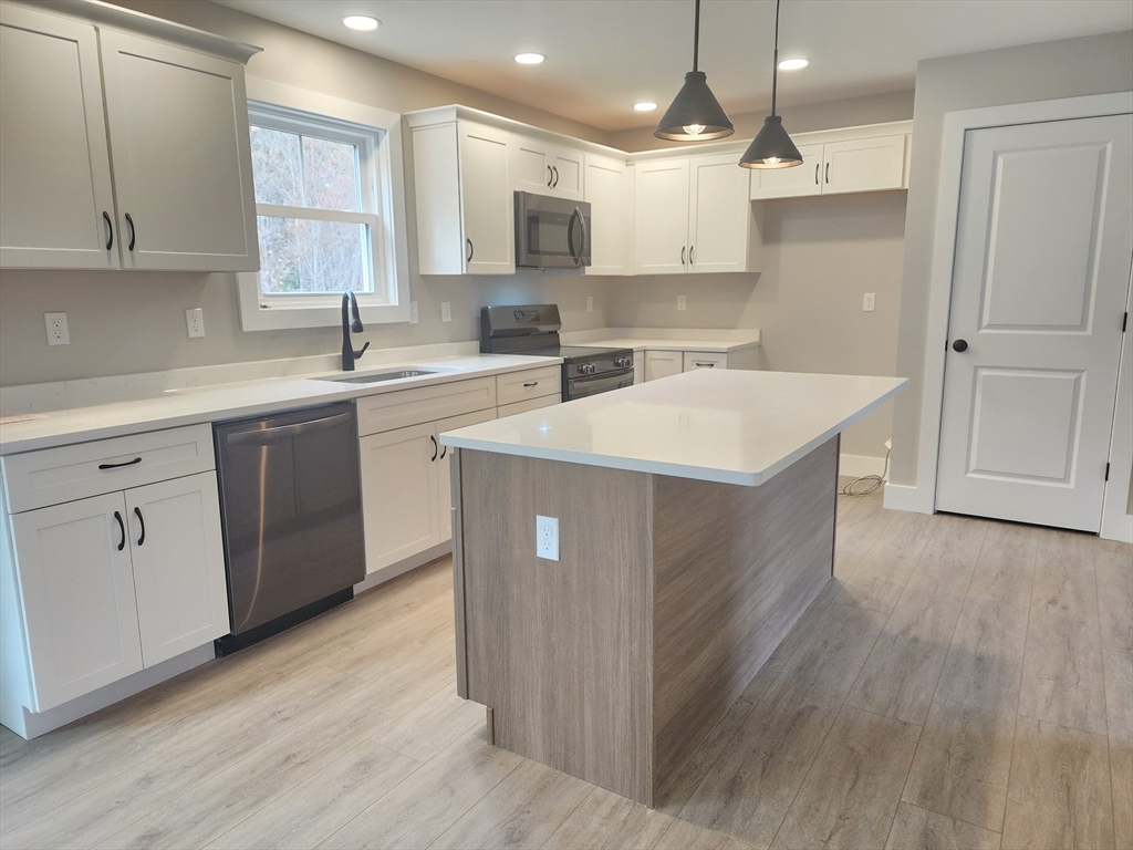 21 Cottage Street Winchendon, MA 01475 - Photo 5 of 12 a kitchen with kitchen island white cabinets appliances and a sink