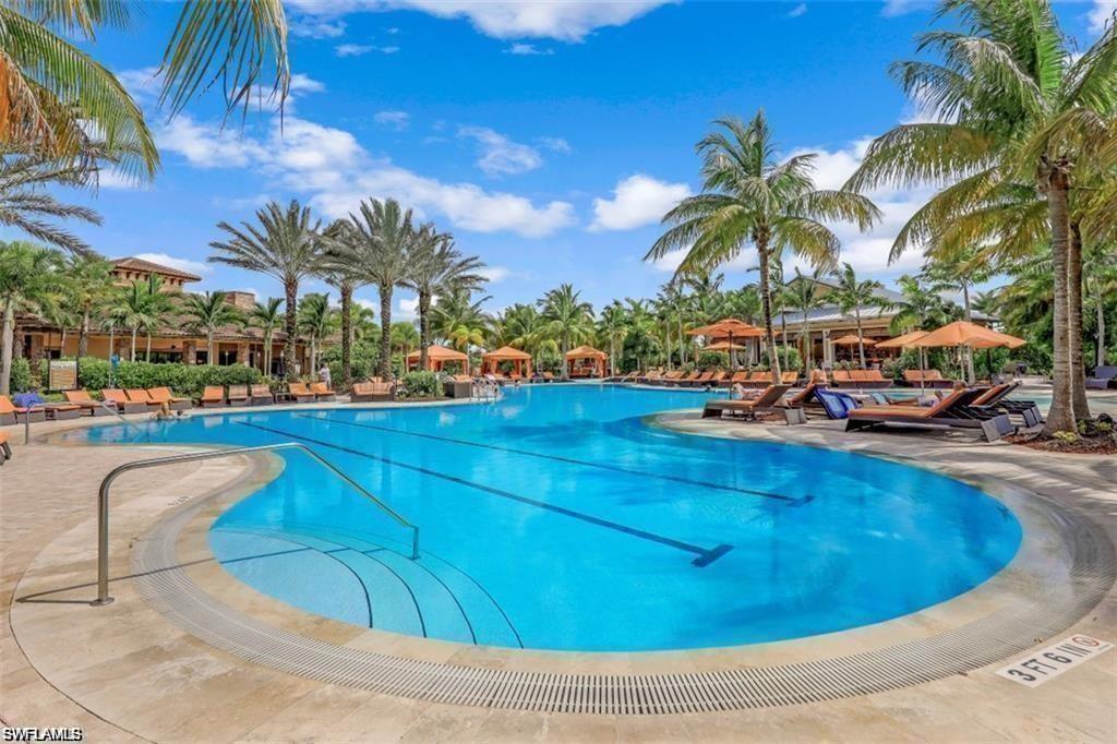 9377 Pocida Court, Unit 202 Naples, FL 34119 - Photo 19 of 30 a view of a swimming pool with a lounge chair and palm trees
