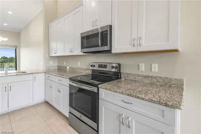 a kitchen with granite countertop white cabinets stainless steel appliances and a sink
