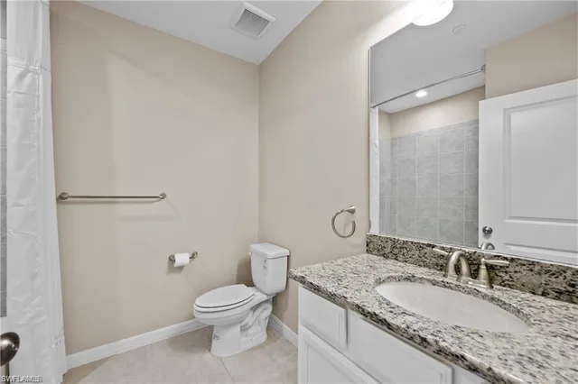 a bathroom with a granite countertop toilet a sink and a mirror