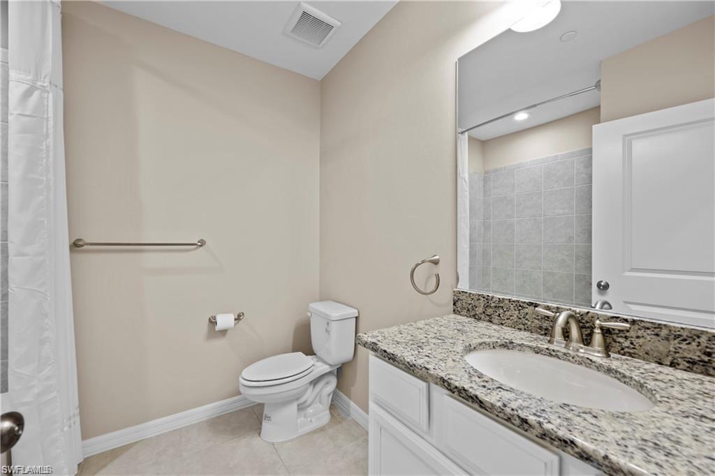 9377 Pocida Court, Unit 202 Naples, FL 34119 - Photo 9 of 30 a bathroom with a granite countertop toilet a sink and a mirror