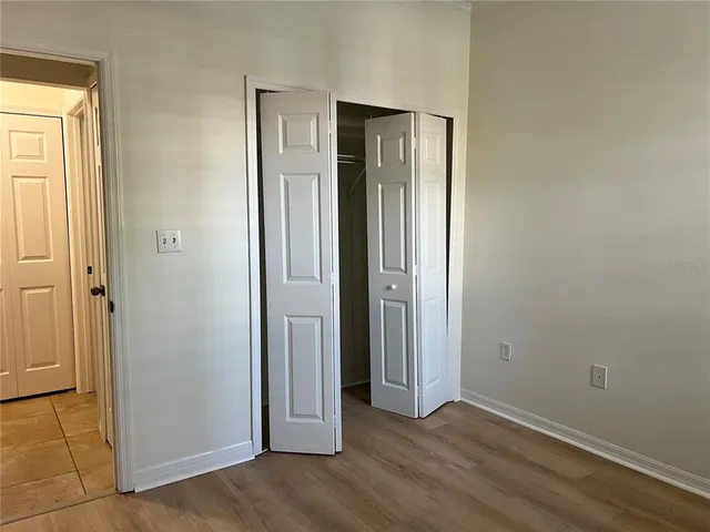 an empty room with wooden floor and closet area