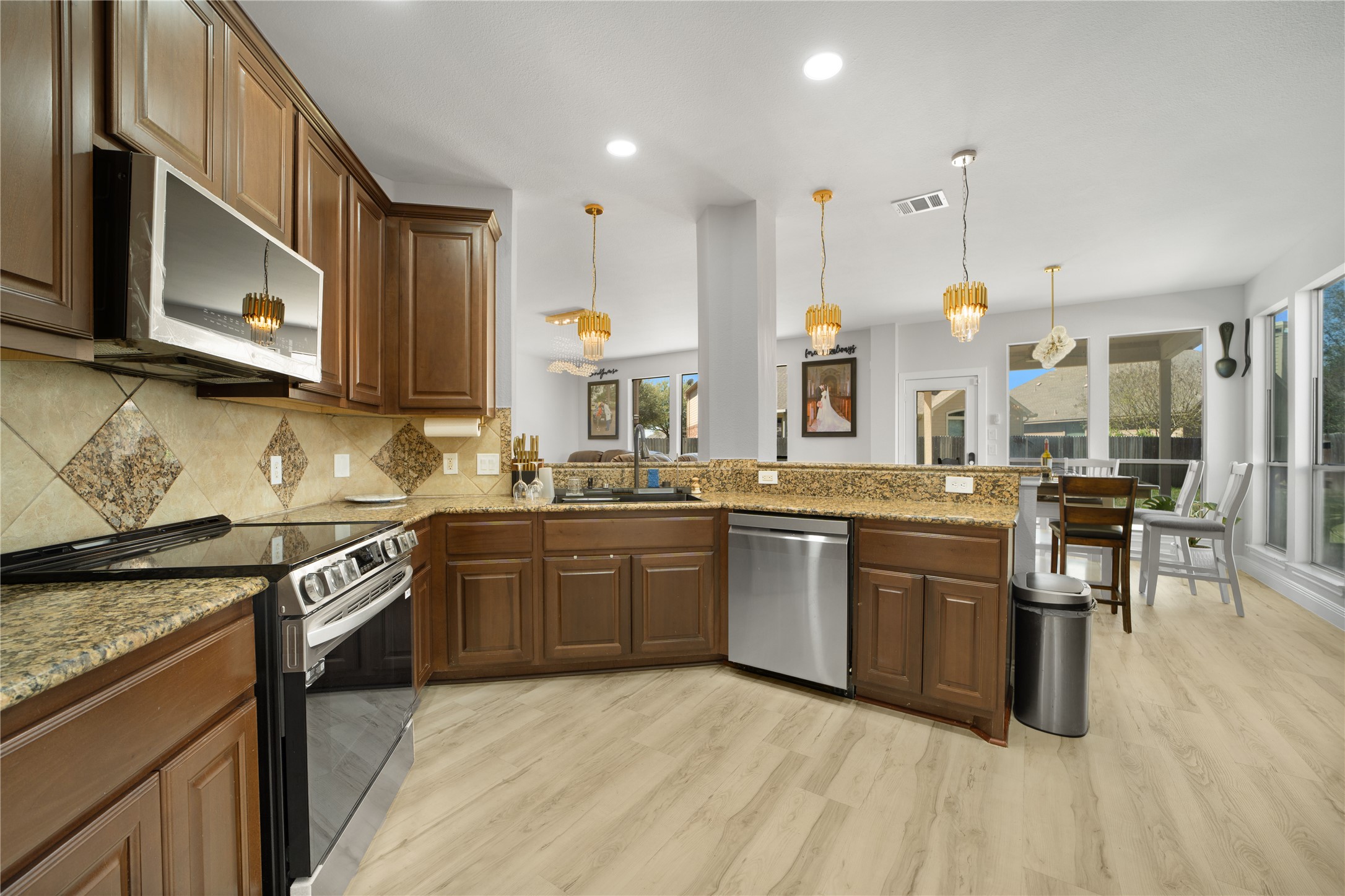 3032 Prairie Bluff Seguin, TX 78155 - Photo 22 of 23 Kitchen with stainless steel appliances, light stone counters, a peninsula, pendant lighting, and light wood-type flooring