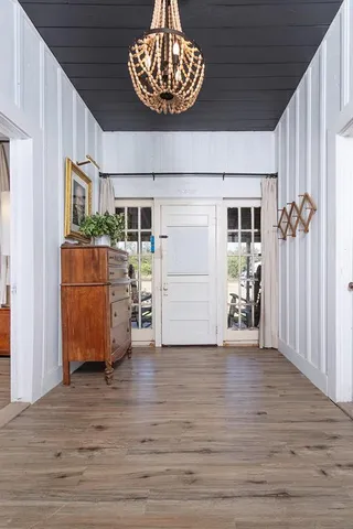 a view of kitchen and an empty room with wooden floor