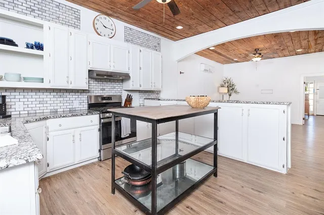 a kitchen with stainless steel appliances kitchen island granite countertop a stove a sink and a refrigerator