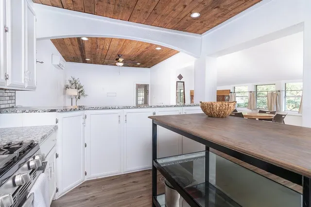 a kitchen with granite countertop a sink a stove and cabinets