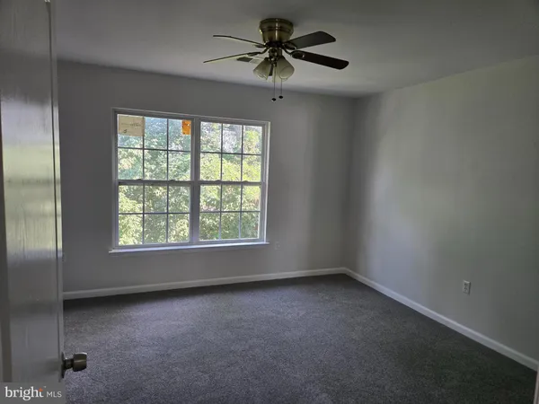 an empty room with a window and a ceiling fan