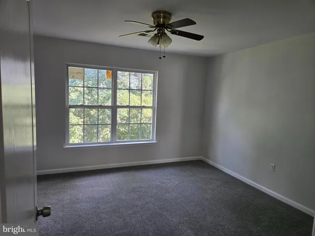an empty room with a window and a ceiling fan