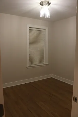 an empty room with wooden floor cabinet and windows