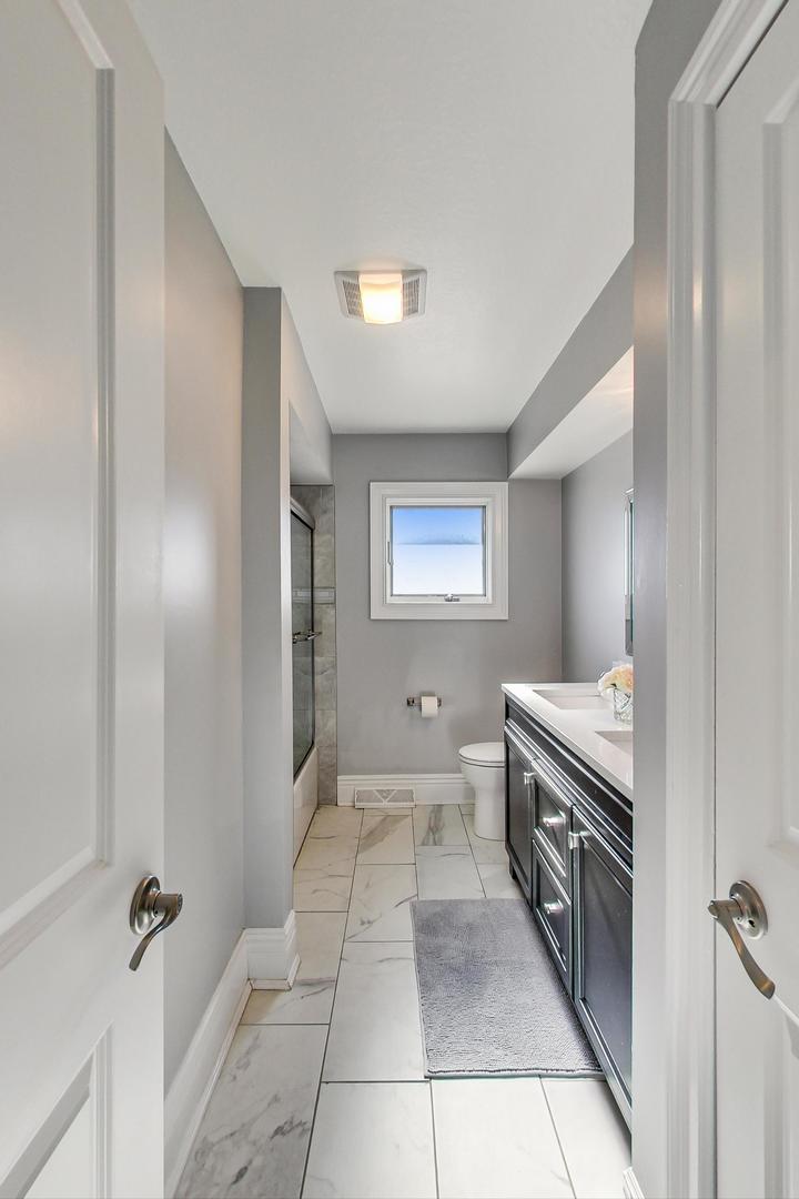 1579 West Holtz Avenue Addison, IL 60101 - Photo 19 of 43 a bathroom with a granite countertop sink a toilet and a mirror