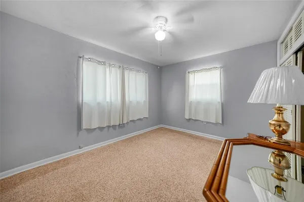 an empty room with a chandelier fan and windows