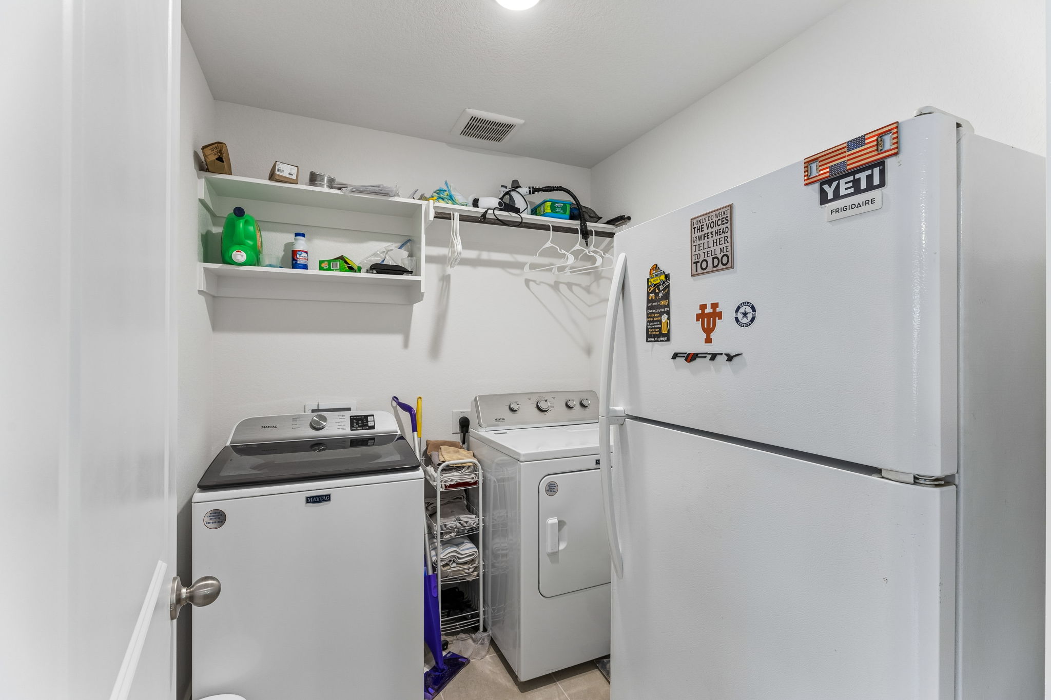 13509 Barn Chime Street Elgin, TX 78621 - Photo 13 of 40 Dedicated laundry area featuring a top-load washing machine, a front-load dryer, and overhead shelving for storage