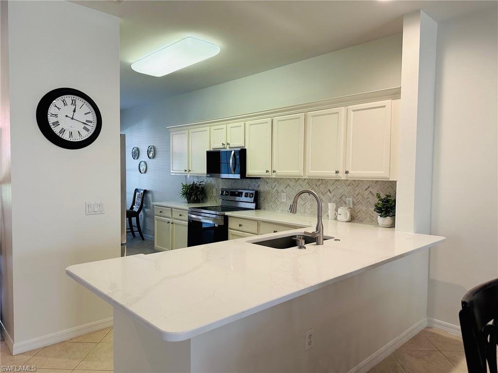 a kitchen with stainless steel appliances granite countertop a sink a stove top oven a clock and a window