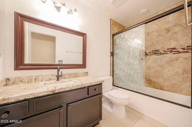 a bathroom with a granite countertop sink mirror vanity and toilet