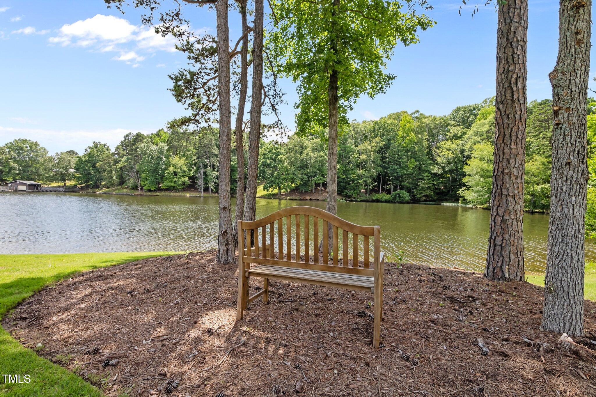 976 Estate Road Semora, NC 27343 - Photo 57 of 69 a view of a lake with a bench and trees around