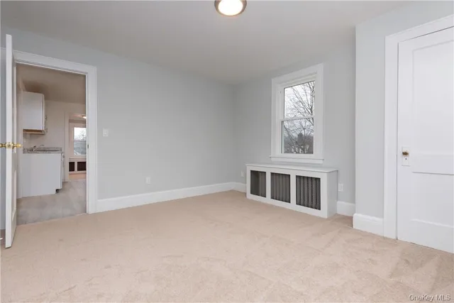 an empty room with windows and fireplace