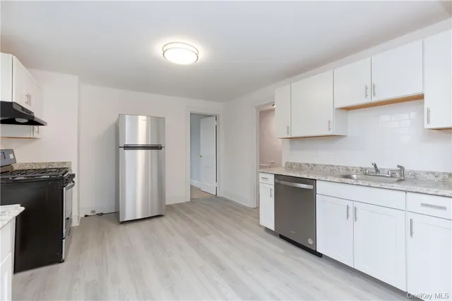a kitchen with granite countertop a refrigerator and a stove top oven