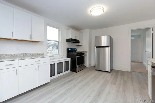 a kitchen with granite countertop a refrigerator and a stove top oven