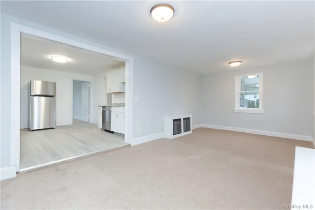 an empty room with windows and refrigerator