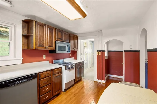 a kitchen with stainless steel appliances granite countertop a stove a sink dishwasher and a refrigerator with wooden floor