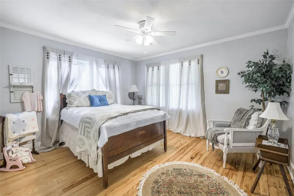 a spacious bedroom with a bed a chair and potted plant on the dresser