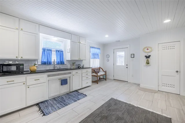 a large white kitchen with a sink and dishwasher with wooden floor