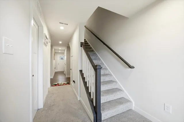 a view of a hallway with staircase and kitchen view