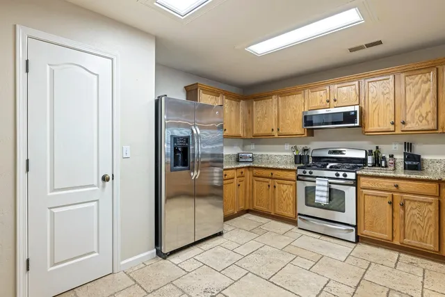 a kitchen with stainless steel appliances granite countertop a stove a sink and a refrigerator