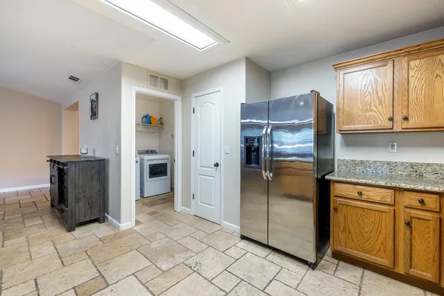 a kitchen with granite countertop a refrigerator and a cabinets
