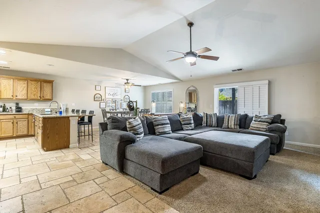 a living room with furniture a chandelier and kitchen view