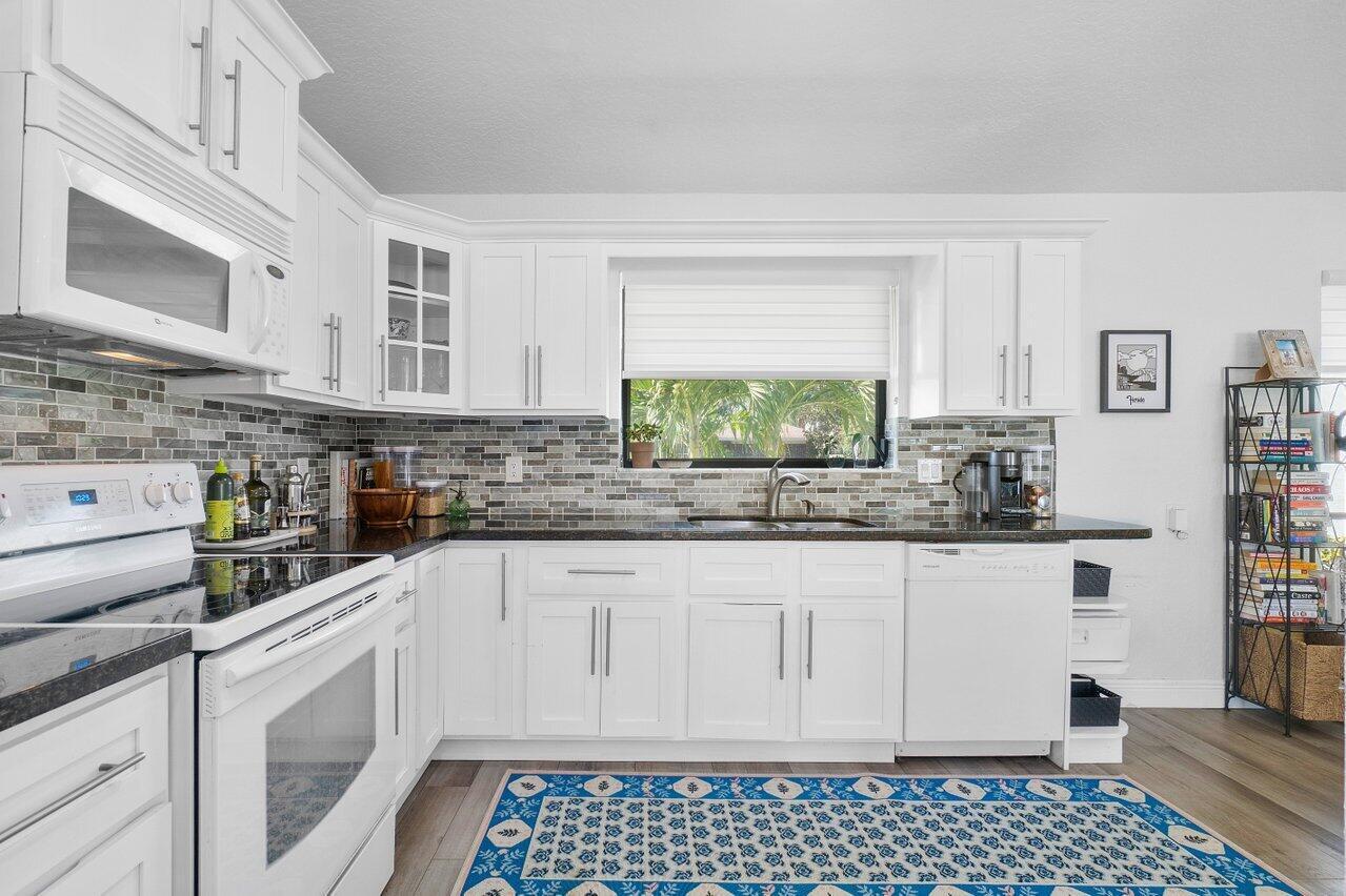 6085 Robinson Street Jupiter, FL 33458 - Photo 12 of 32 a kitchen with stainless steel appliances granite countertop a stove a sink and a white cabinets