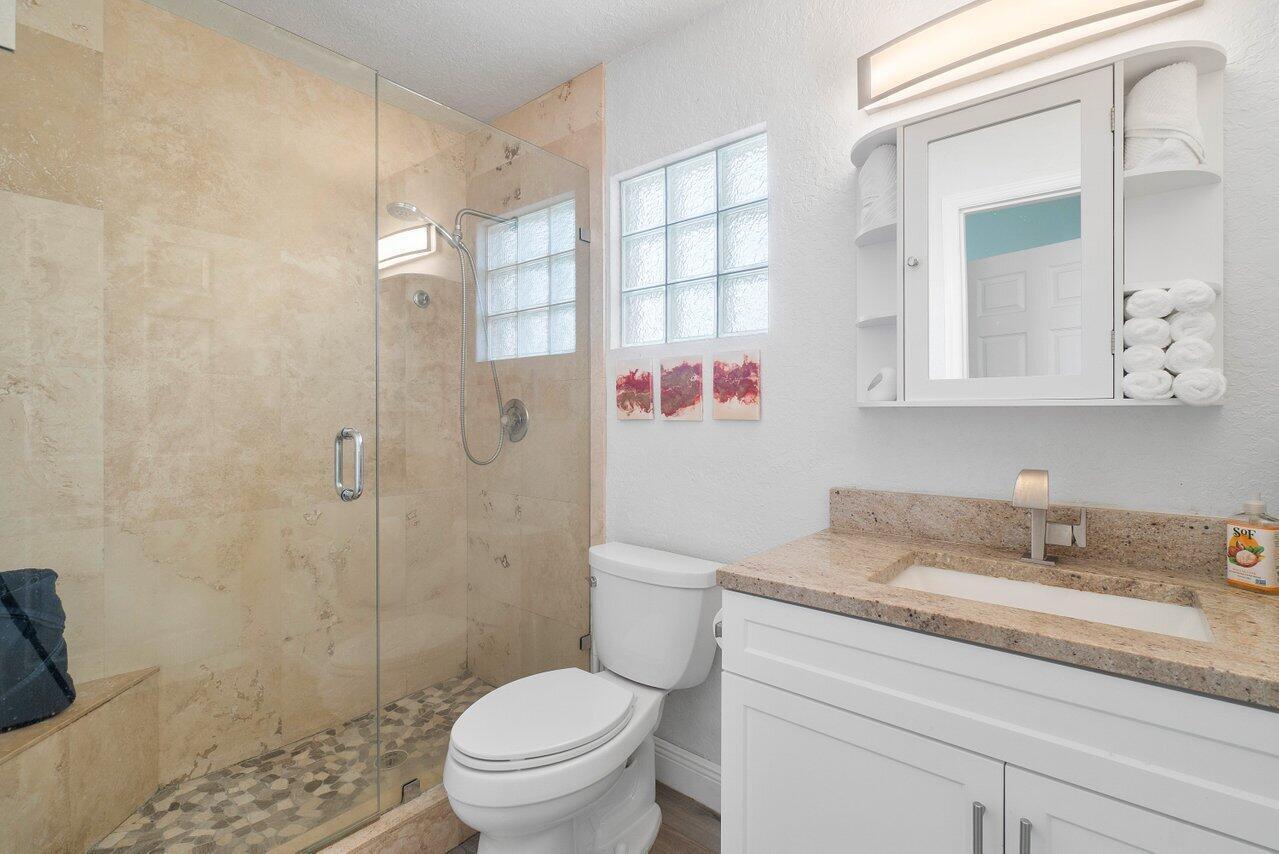 6085 Robinson Street Jupiter, FL 33458 - Photo 19 of 32 a bathroom with a granite countertop sink a toilet and shower