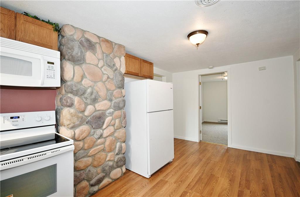66 Chestnut Street Ellsworth, PA 15331 - Photo 11 of 28 a view of a refrigerator in kitchen and an empty room with wooden floor